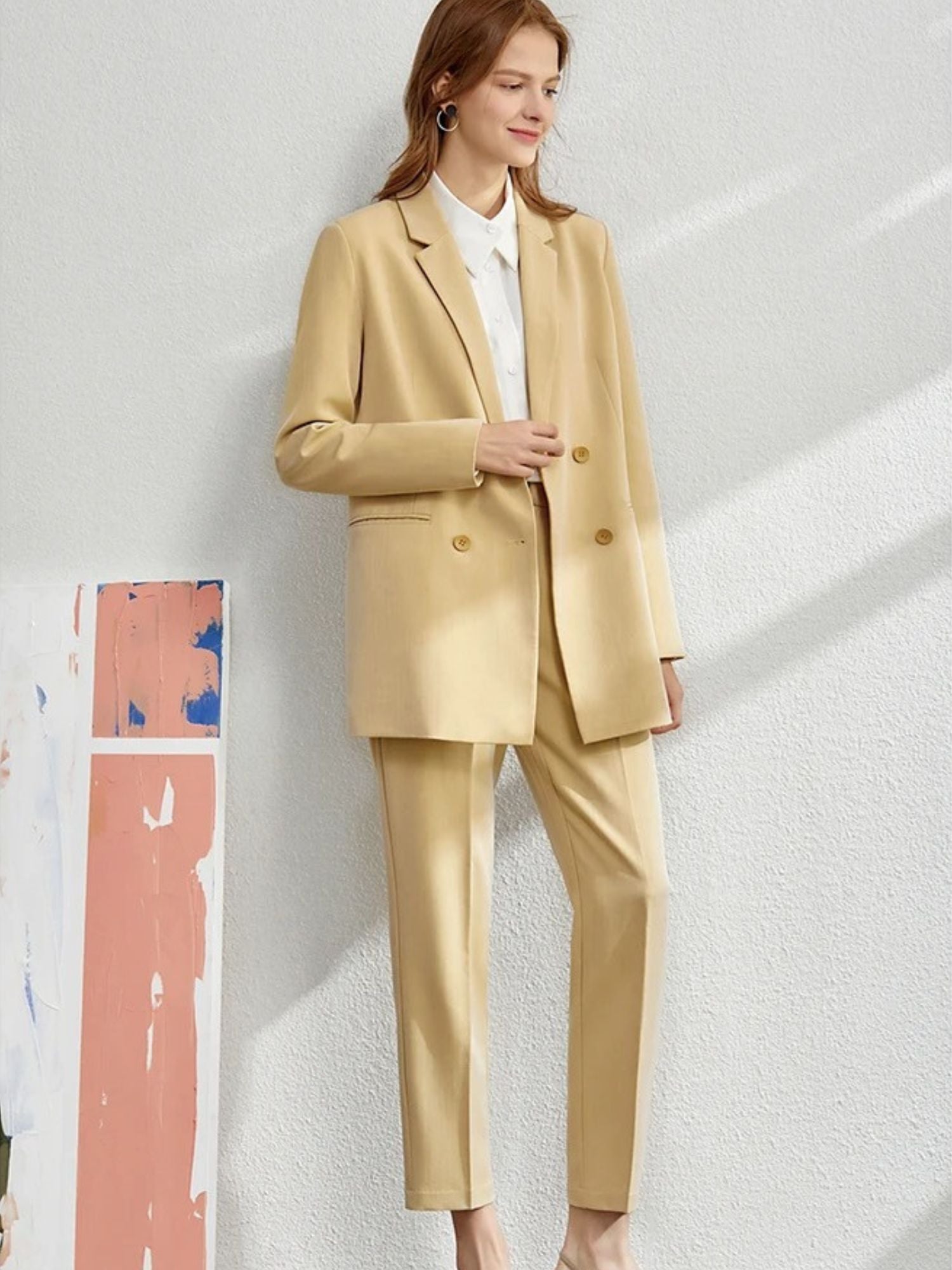 Damen-Hosenanzug in Beige, Modell stehend mit Tasche.