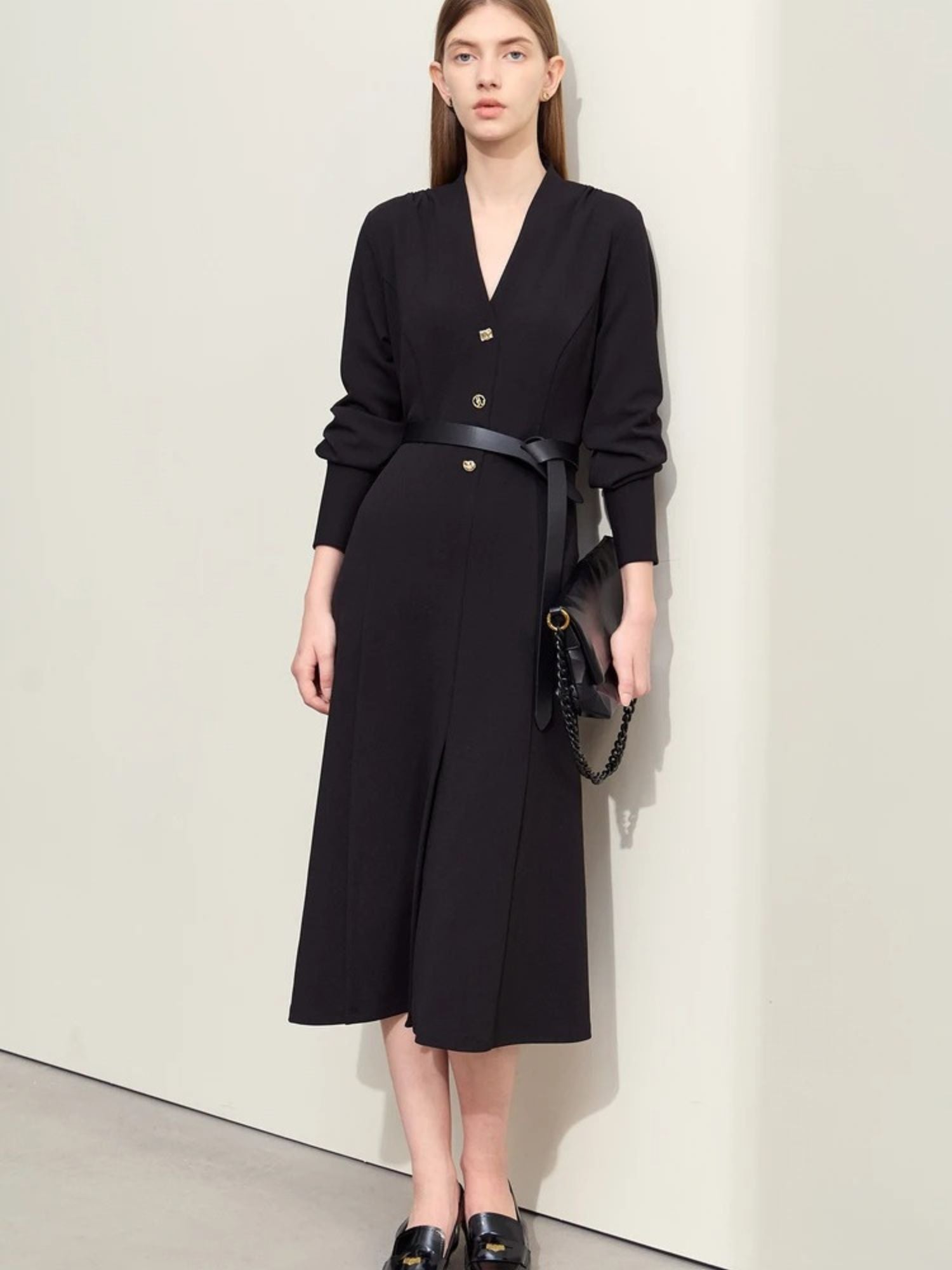 Schwarzes Midikleid mit V-Ausschnitt, Modell frontal mit Tasche.