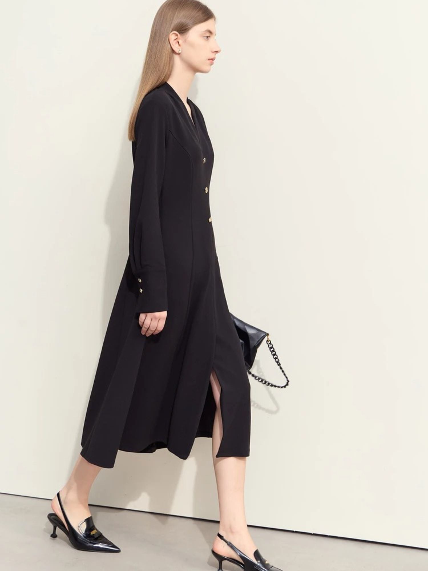 Schwarzes Midikleid mit V-Ausschnitt und Goldknöpfen am Ärmel, Modell gehend.