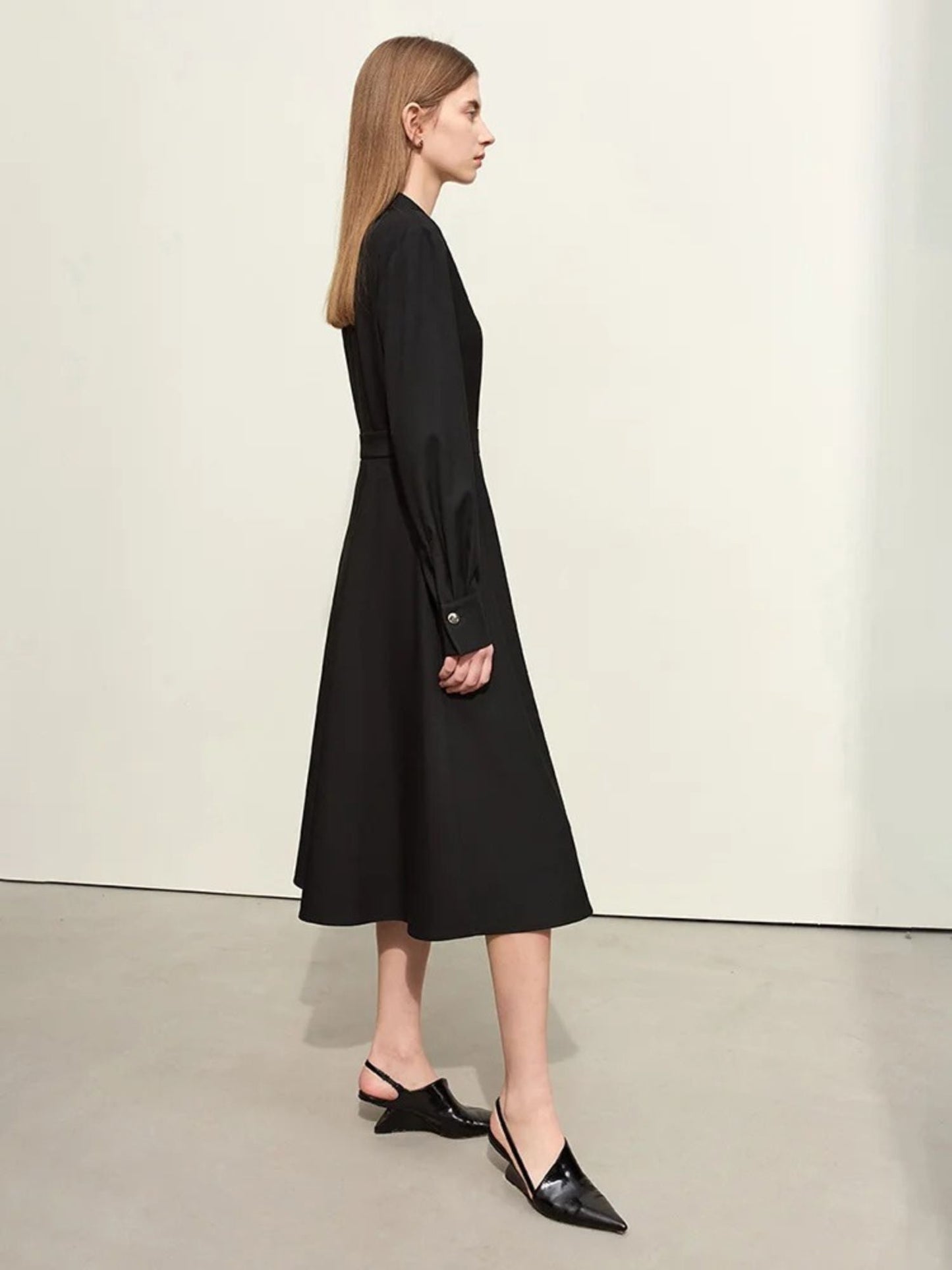 Schwarzes Midikleid mit Gürtel, seitliche Ansicht des Modells.
