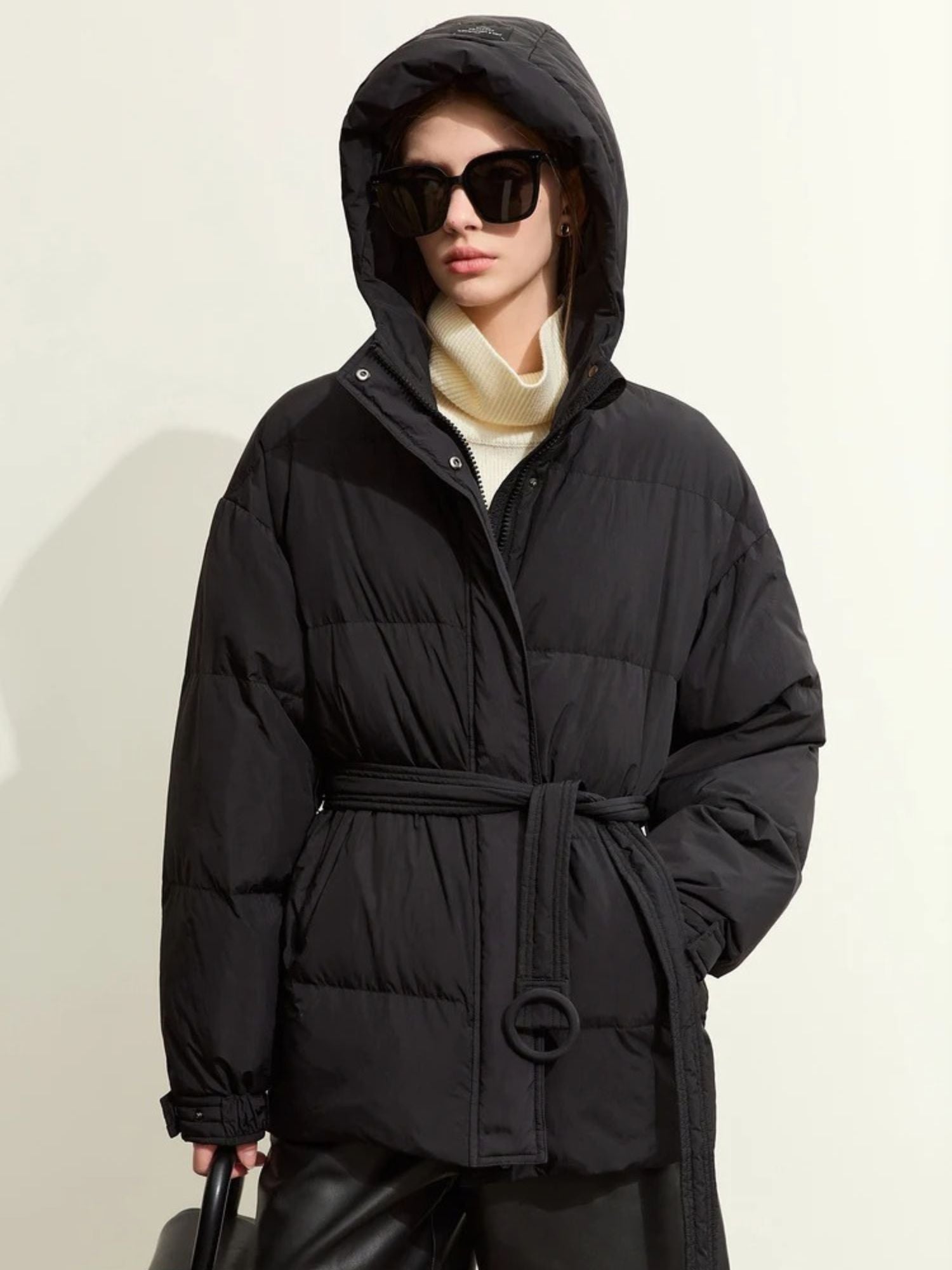 Schwarzer Daunenmantel mit Kapuze, geschlossen, Modell mit Sonnenbrille.