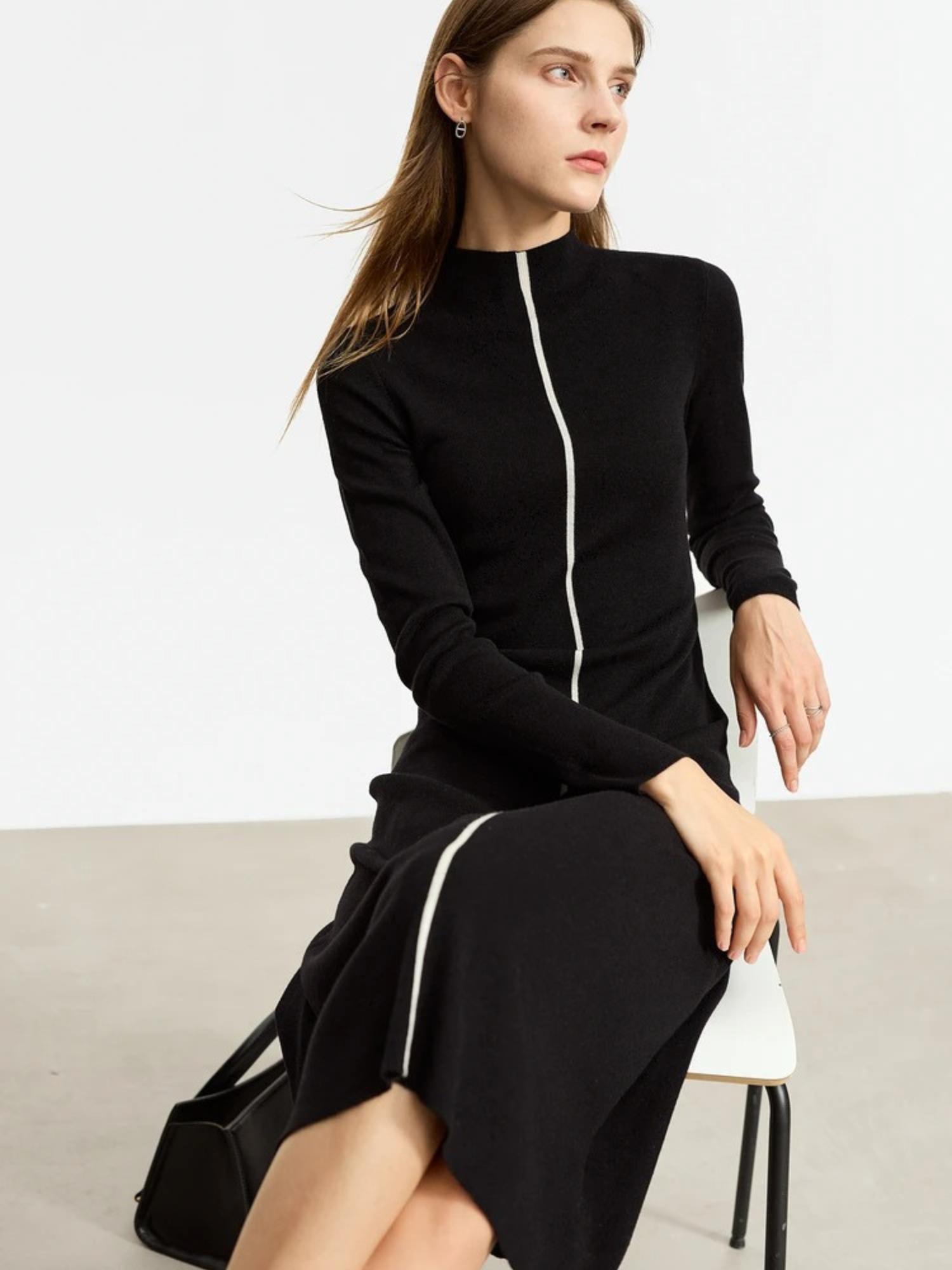 Schwarzes Strickkleid mit Reißverschluss, Modell sitzend.