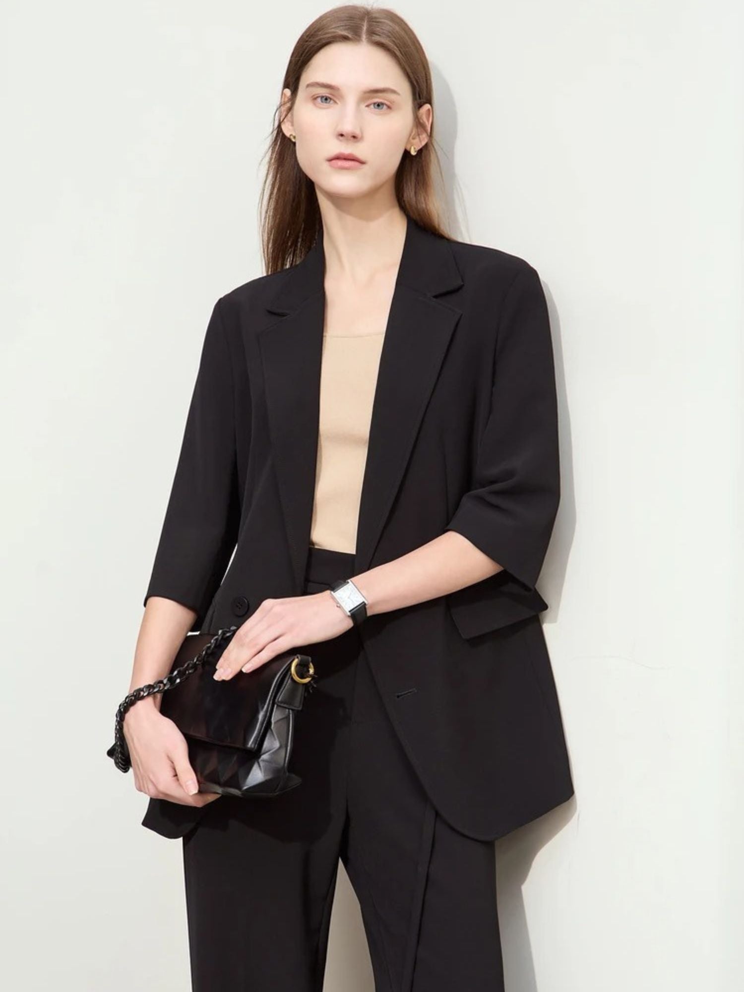 Schwarzer Hosenanzug mit 3/4-Arm-Blazer, Modell frontal mit Clutch.