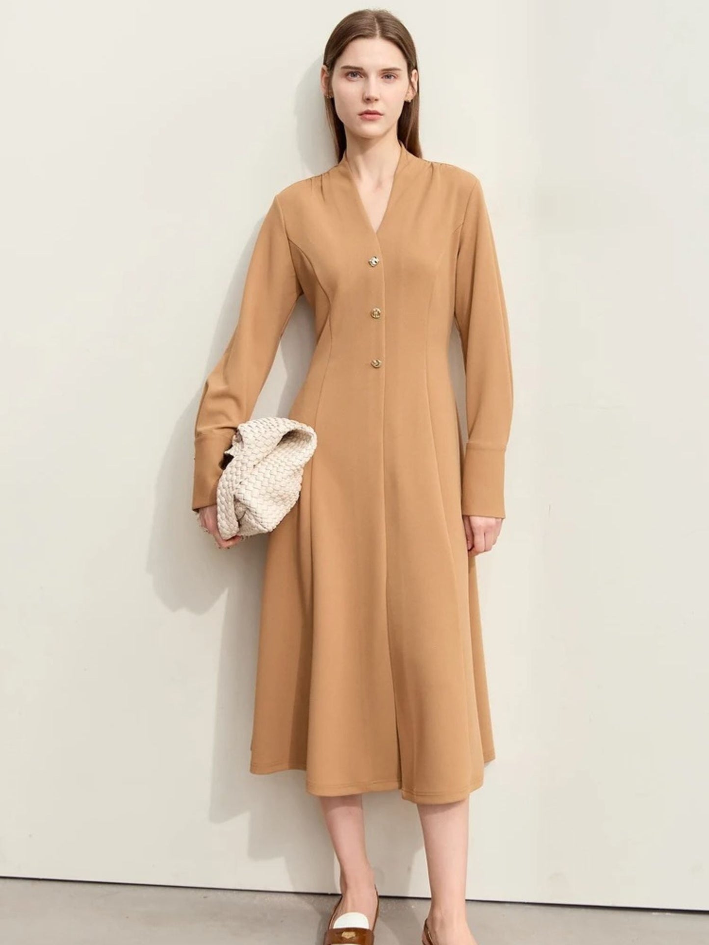 Beiges Midikleid mit V-Ausschnitt, Modell frontal mit Tasche.