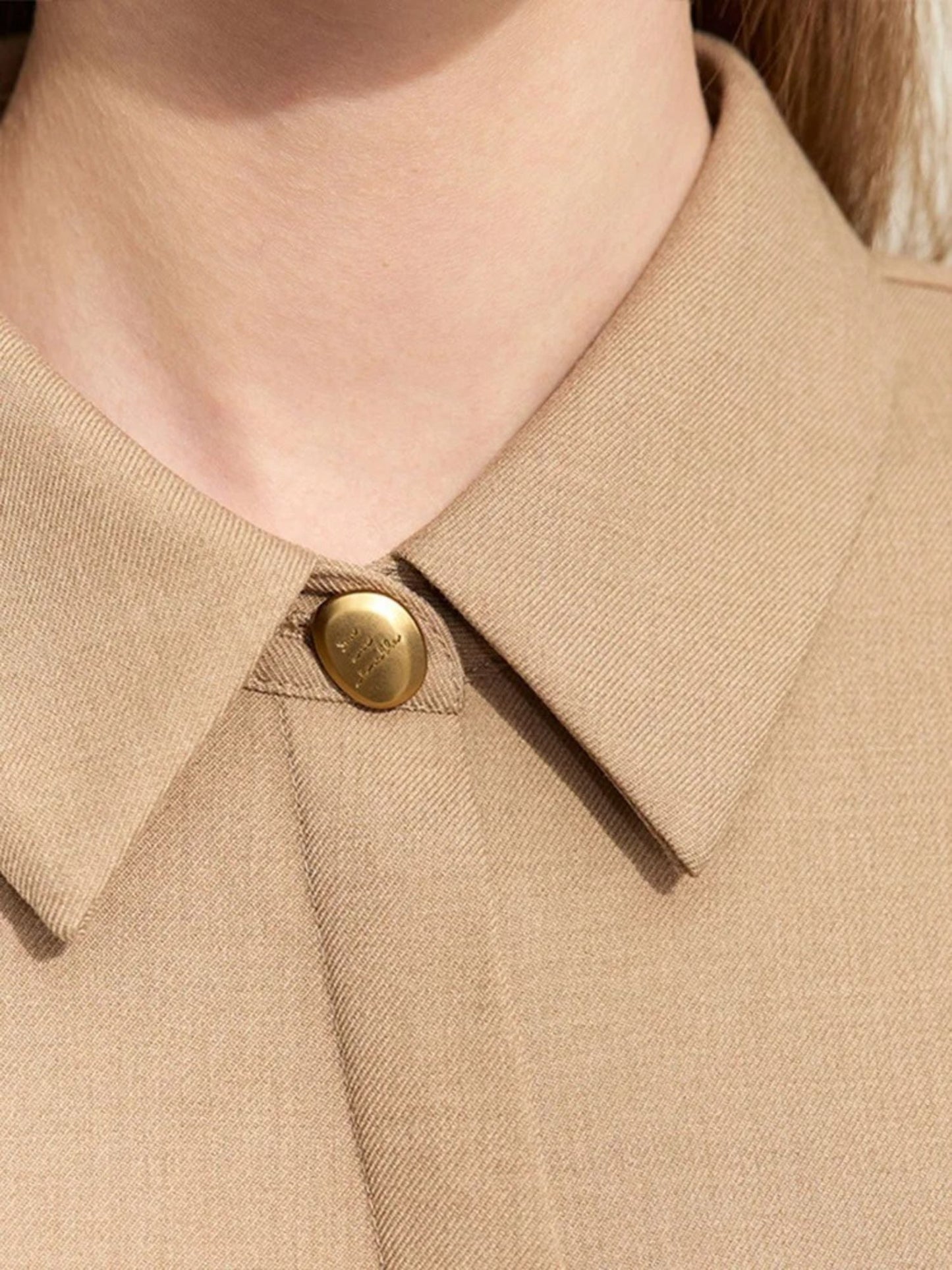Nahaufnahme: Kragen und Knopf des beigen Hemdblusenkleids.