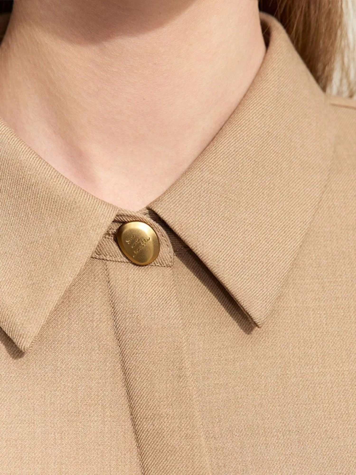 Nahaufnahme: Kragen und Knopf des beigen Hemdblusenkleids.