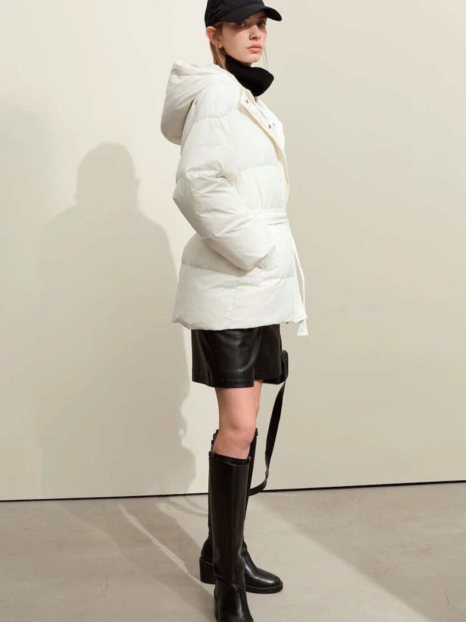 Schwarzer Daunenmantel mit Kapuze, frontale Ansicht, Modell mit Tasche.