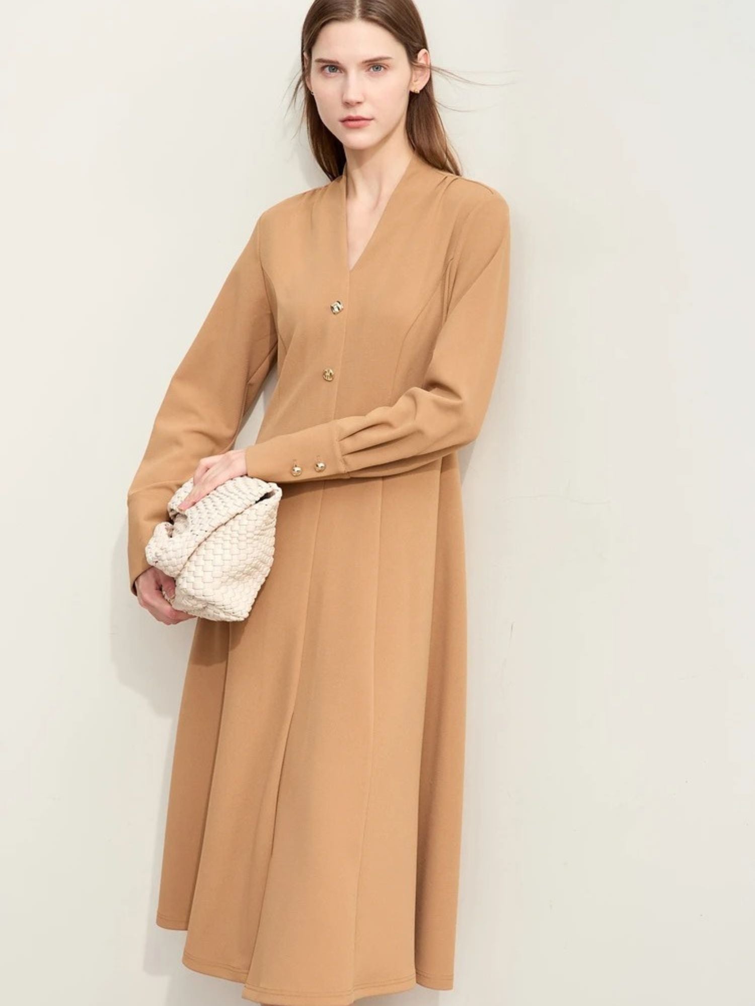 Beiges Midikleid mit V-Ausschnitt, Modell frontal mit Tasche.