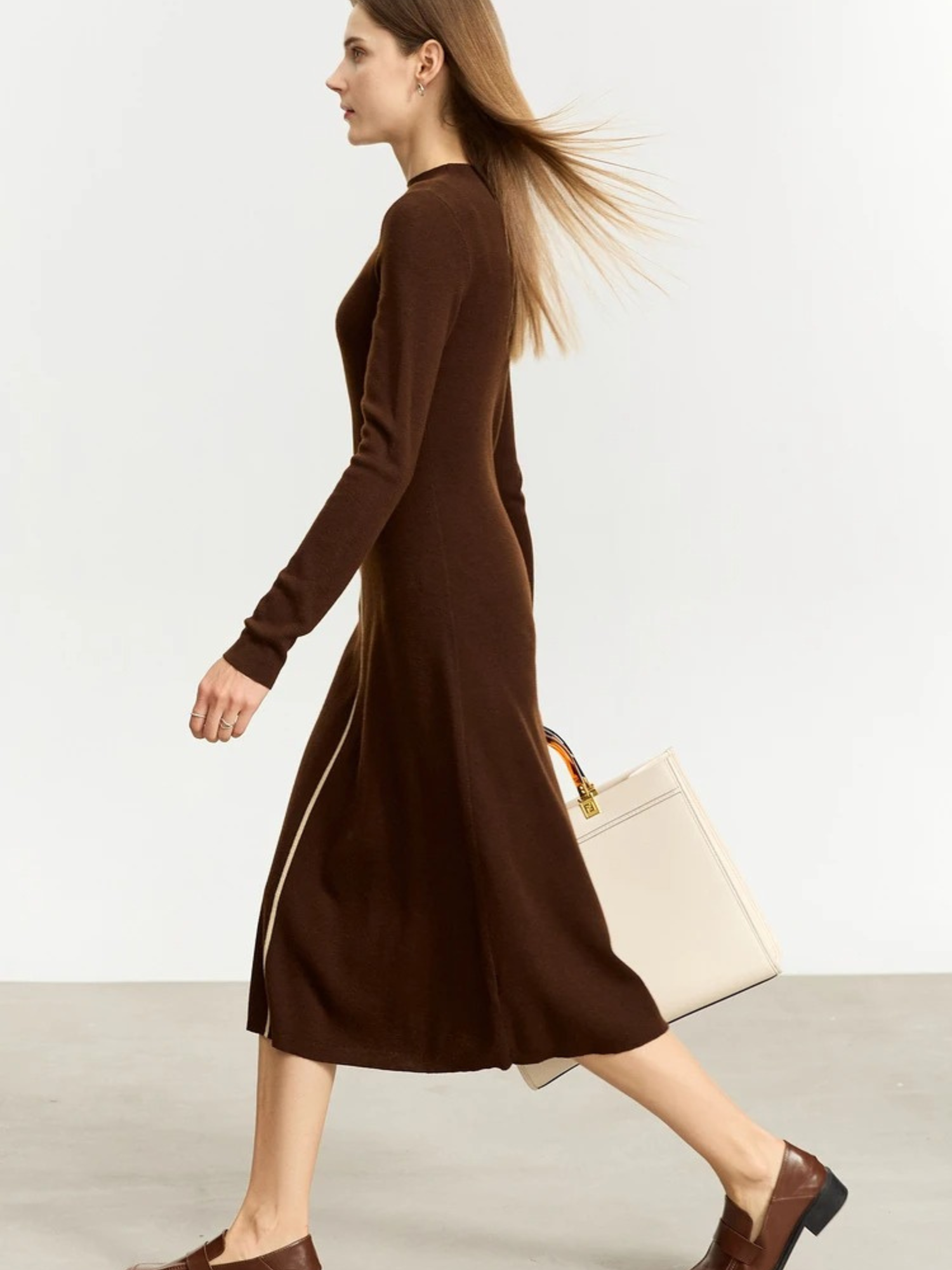 Braunfarbenes Strickkleid, Modell gehend mit Tasche.