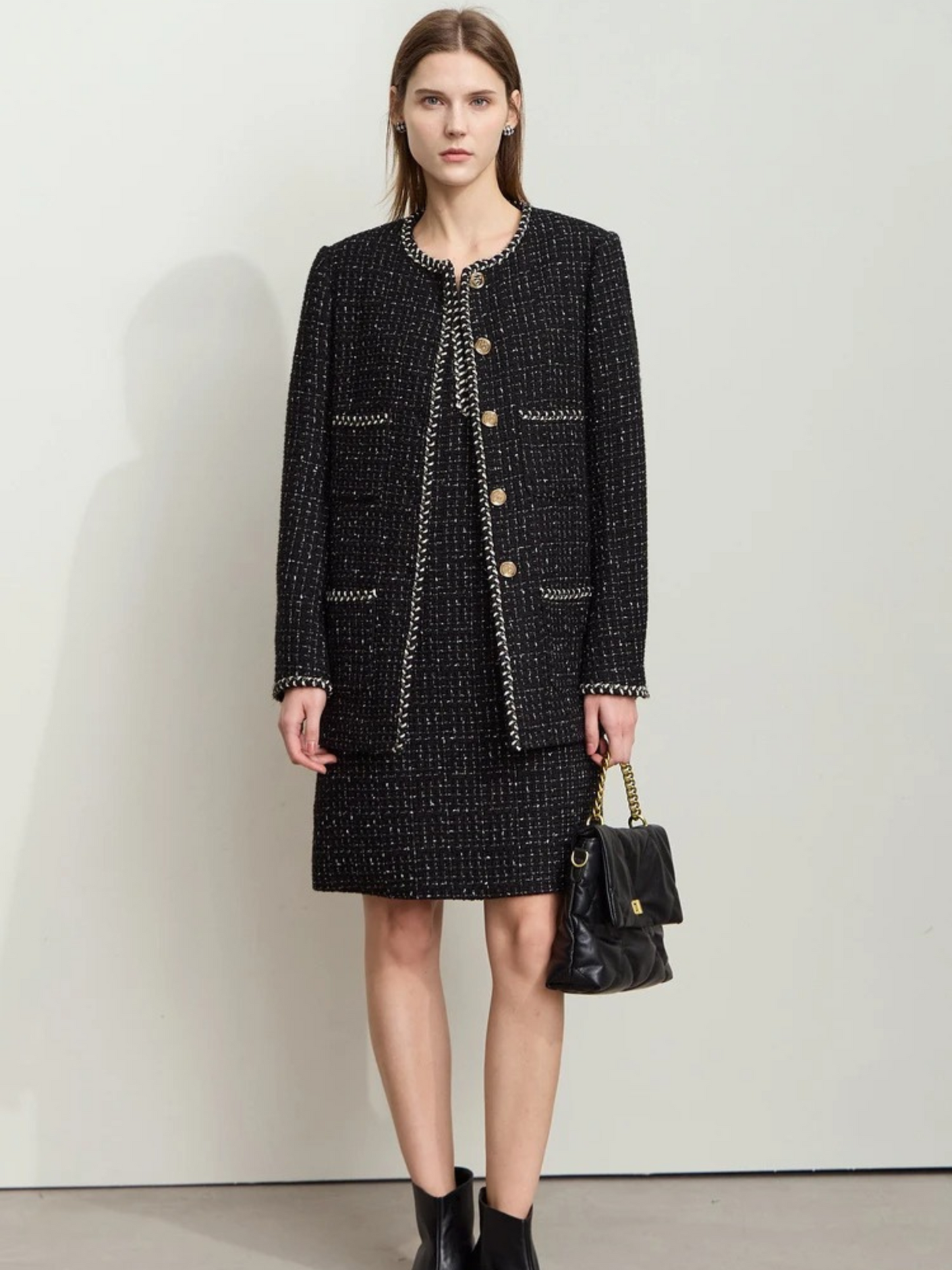 Schwarzes Tweed-Zweiteiler-Set mit Goldknöpfen, Modell mit Handtasche.