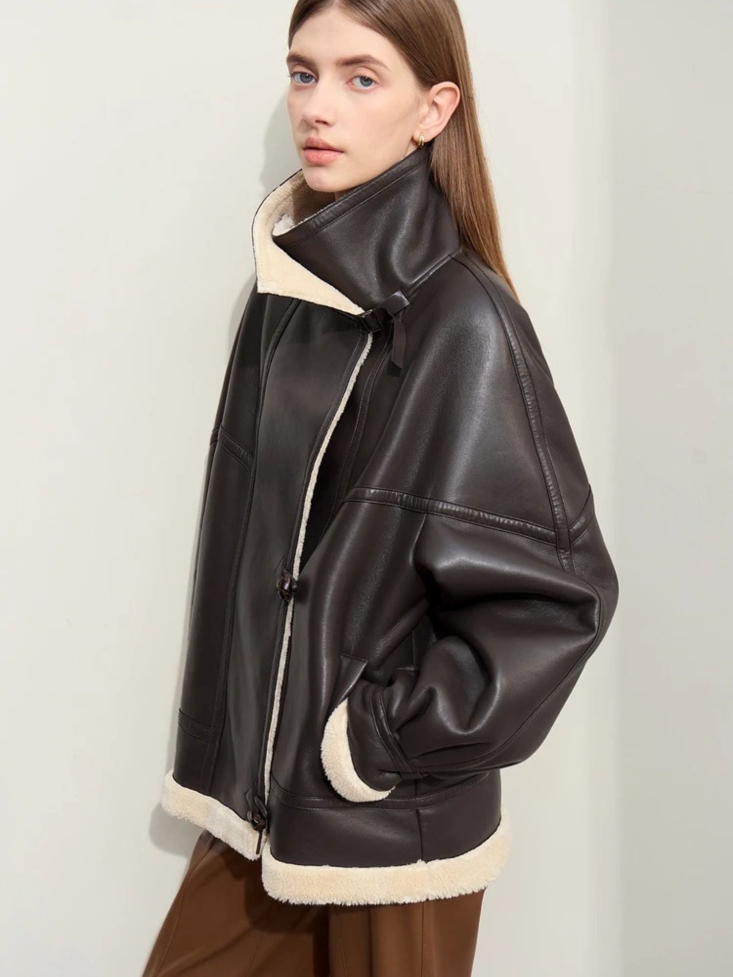 Braune Lederimitat-Jacke mit Shearling-Kragen, seitliche Ansicht.