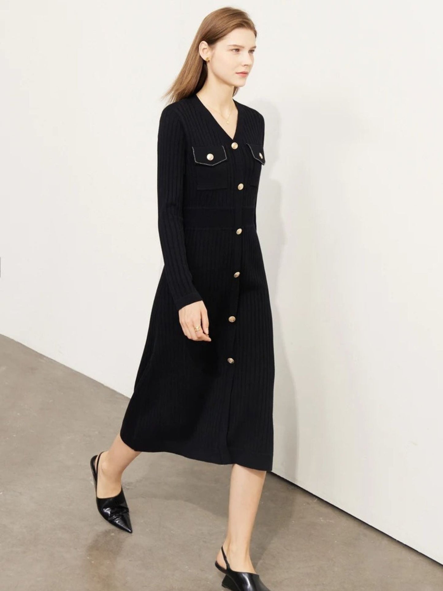 Schwarzes Strick-Midikleid mit Knopfleiste und Brusttaschen, Modell gehend.