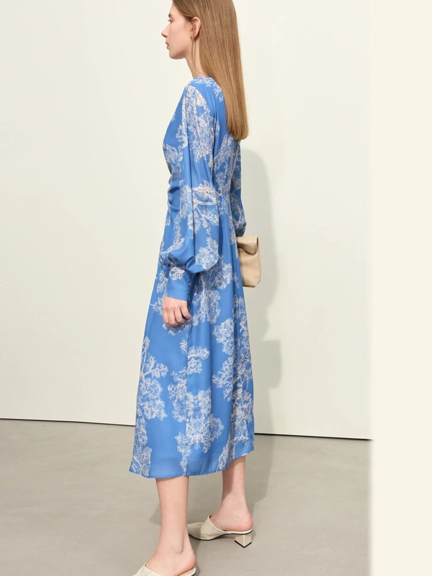 Blaues Midikleid mit Blumenmuster und V-Ausschnitt, Modell seitlich mit Tasche.