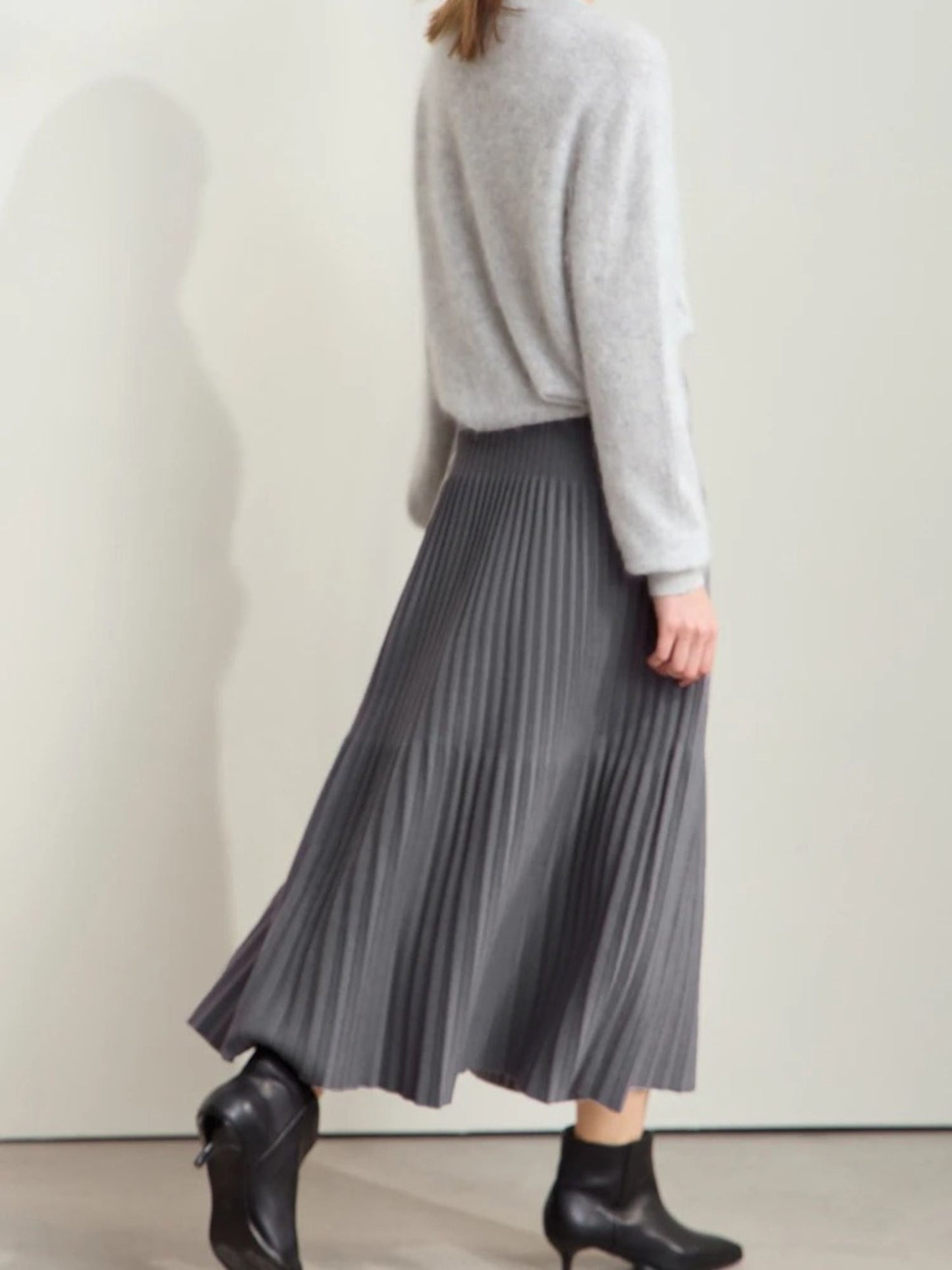 Grauer Plisseerock mit Farbkontrast, Modell frontal mit Stiefeletten.