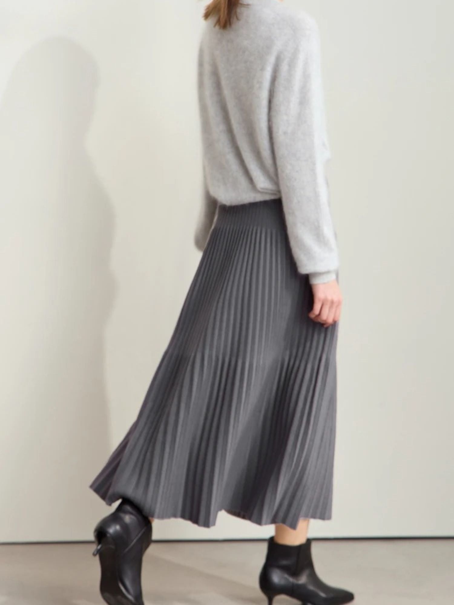 Grauer Plisseerock mit Farbkontrast, Modell frontal mit Stiefeletten.
