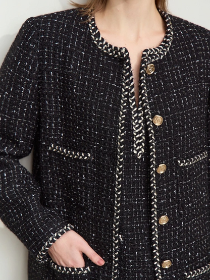 Detailaufnahme: Schwarze Tweed-Jacke mit Goldknöpfen und Rundhalsausschnitt.

