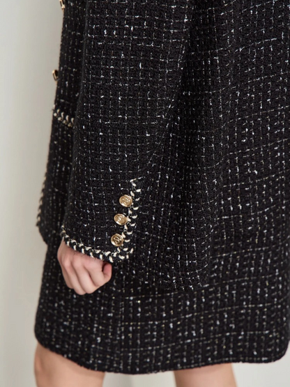 Detailaufnahme: Ärmelabschluss der schwarzen Tweed-Jacke mit Goldknöpfen.