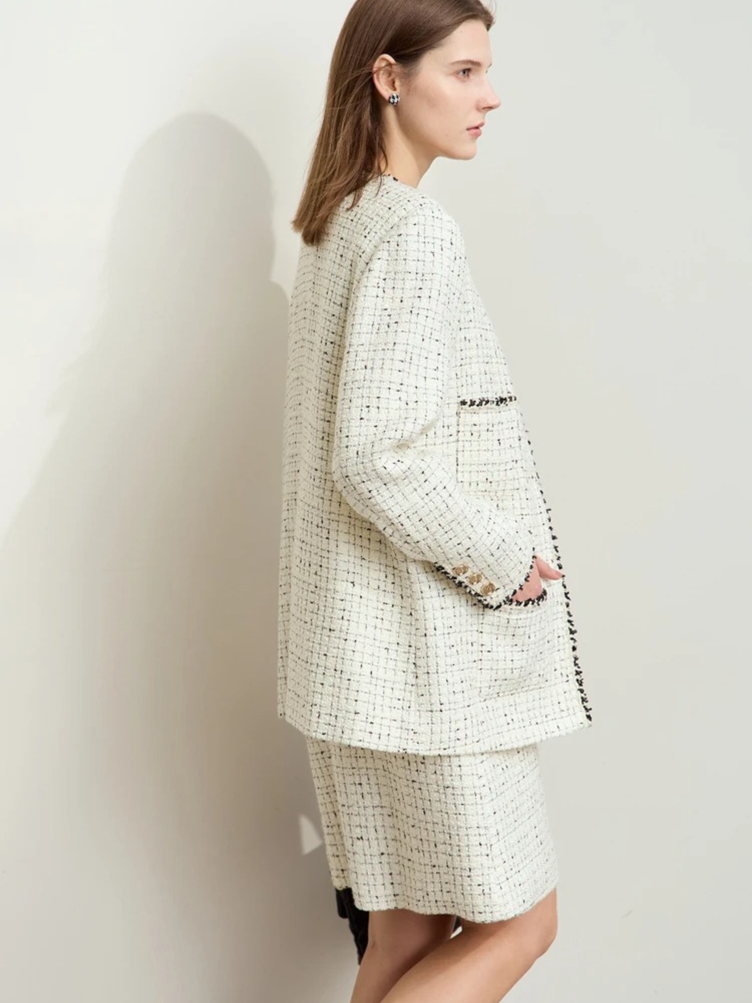 Weißes Tweed-Zweiteiler-Set mit Goldknöpfen, Modell mit Handtasche.