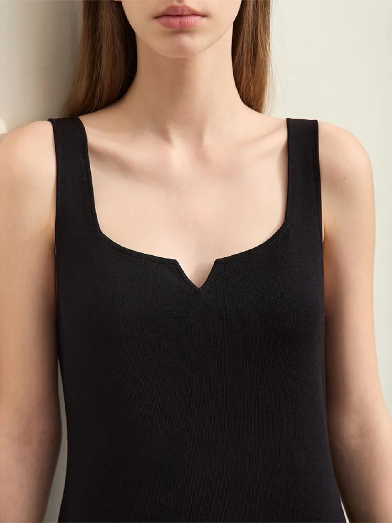 A close up of the v cut out design on the neckline of a black dress.